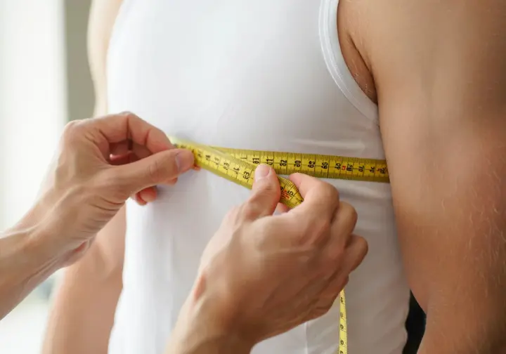 Hands using a measuring tape to measure chest girth, crucial for mastering wader fit.