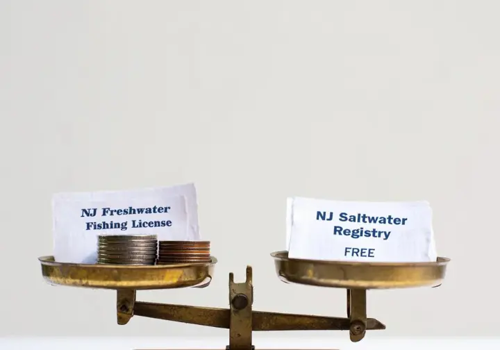Balance scale visually comparing the cost ($) of a NJ freshwater license versus the FREE NJ saltwater registry.