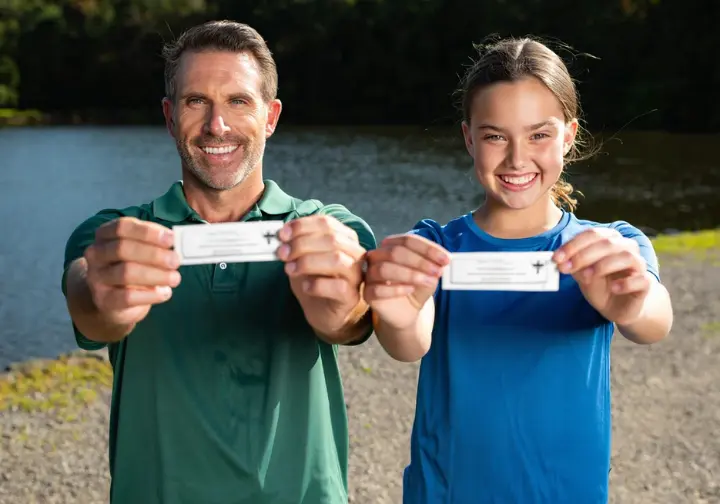 Two friends happily displaying their discounted NJ Fishing Buddy Licenses, representing special license programs.