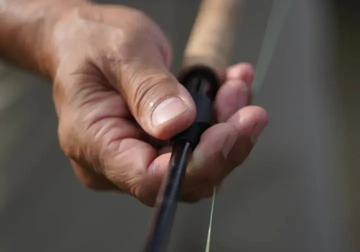 Hand gripping an Ugly Stik GX2 rod handle, subtly illustrating the potential downside of limited sensitivity.