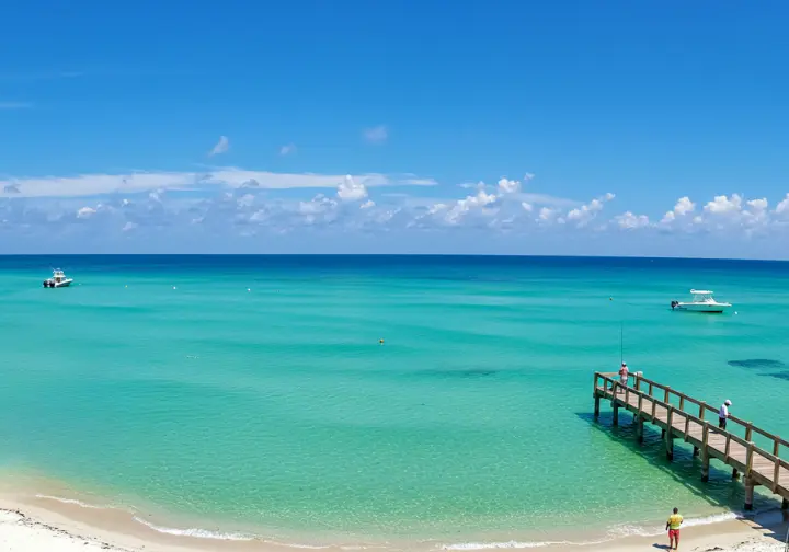 Panoramic view of Panama City Beach with a fisherman on a pier reeling in a fish. 