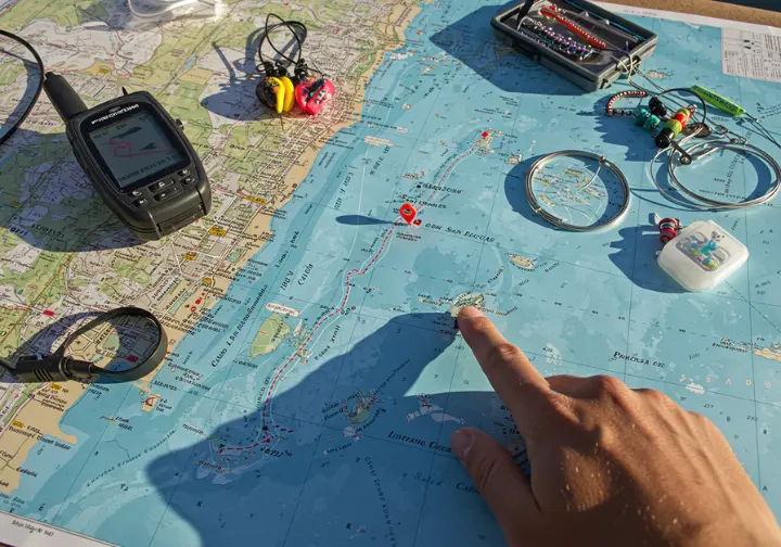 Planning a fishing trip in Cabo San Lucas with a map, GPS, and fishing gear, showcasing the preparation for March fishing.