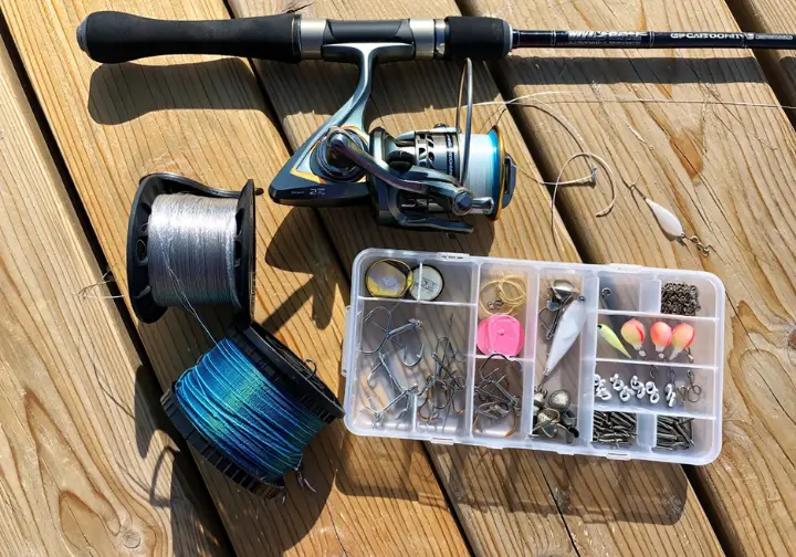 Essential components laid out for assembling a first saltwater fishing kit: rod, reel, braid, leader, hooks, sinkers, jigs