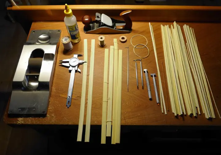 Overhead view of a workbench displaying essential tools and materials needed for building your own bamboo fly rod from culm.