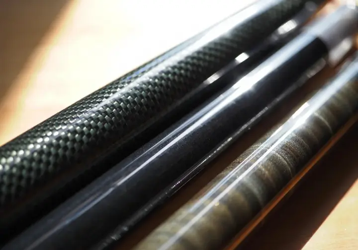 Close-up comparison highlighting the different surface textures of fishing rod blank materials: graphite, fiberglass, and composite.