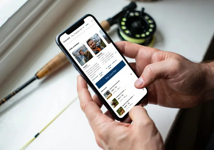 Booking a California fly fishing guide trip online via a guide service website shown clearly on a smartphone screen.