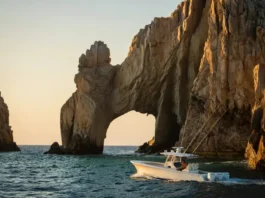 Iconic Cabo San Lucas arch at sunrise with a sportfishing boat nearby, representing the ultimate fishing guide destination.