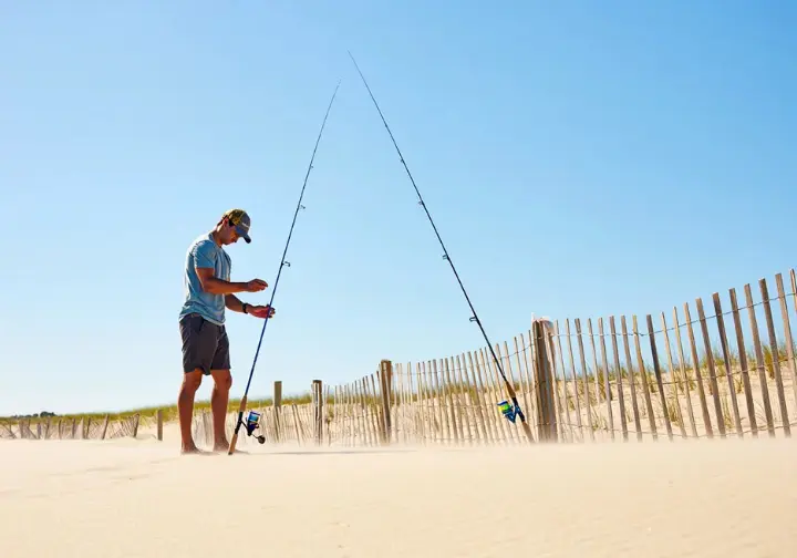 Angler comparing two different surf rods on a beach to select the ideal one for their needs.