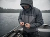 Best Rain Gear for Fishing and Why Cheap Sets Fail Angler in rain gear for fishing retying a lure in steady rain at the stern of a small aluminum boat
