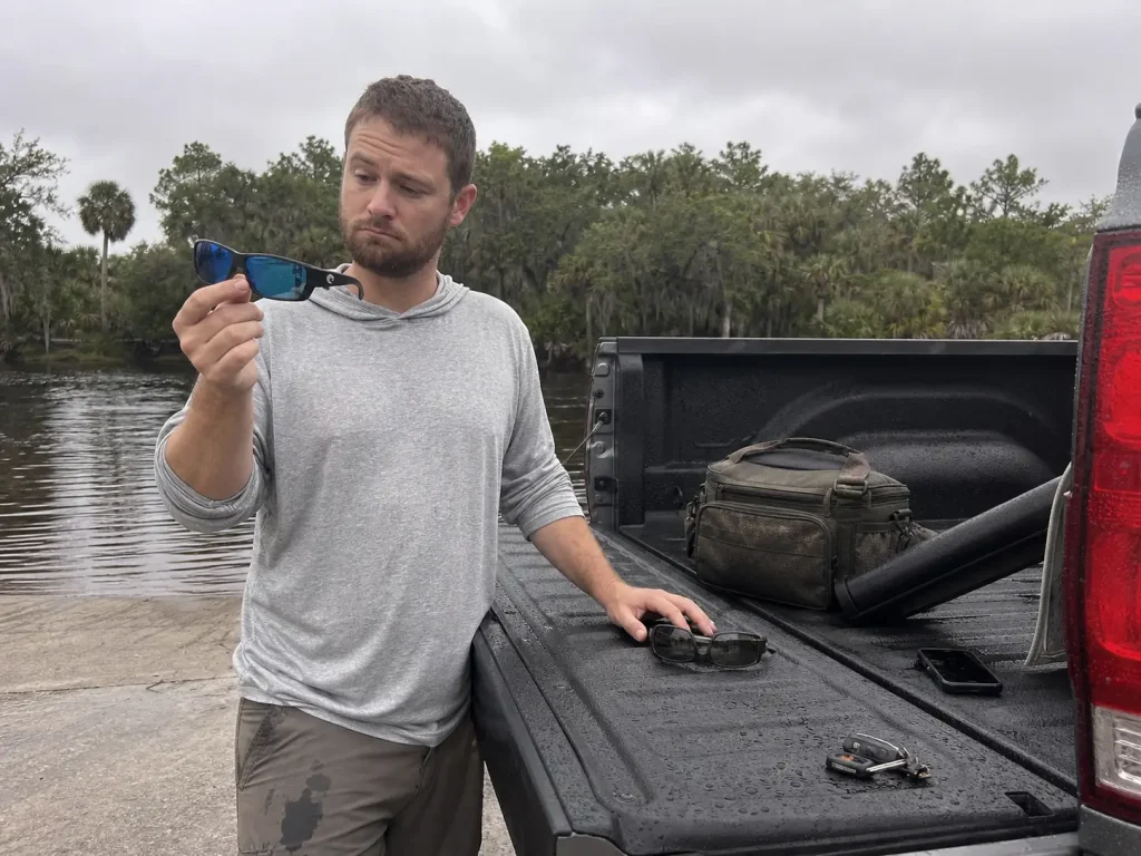 Angler weighing a premium pair of polarized fishing sunglasses against a budget pair at the ramp