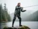 Match Your Rain Gear to Your Fishing: A 2025 Buyer’s Guide A full-body shot of a man in a full rain suit and boots fishing from a rocky shoreline on a rainy, overcast day.