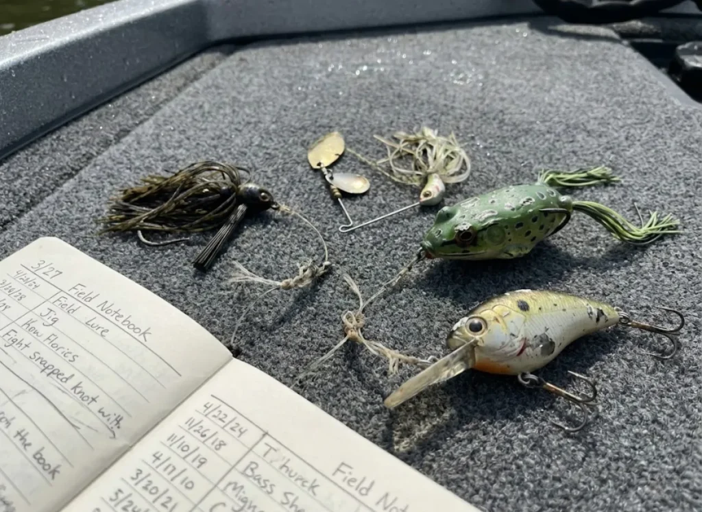 Assortment of used bass fishing lures laid out on a boat deck for comparison and testing.