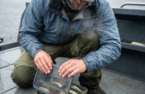 Best Fishing Tackle Box: 2026 Rust & Water Tests An angler opening a waterproof tackle box on a rainy boat deck, revealing dry lures inside despite the storm.