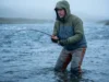 Best Fly Fishing Waders: Tested for Fit & Longevity An angler standing waist-deep in a cold river wearing durable fly fishing waders, fighting a fish in the current.