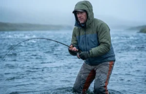 Best Fly Fishing Waders: Tested for Fit & Longevity An angler standing waist-deep in a cold river wearing durable fly fishing waders, fighting a fish in the current.