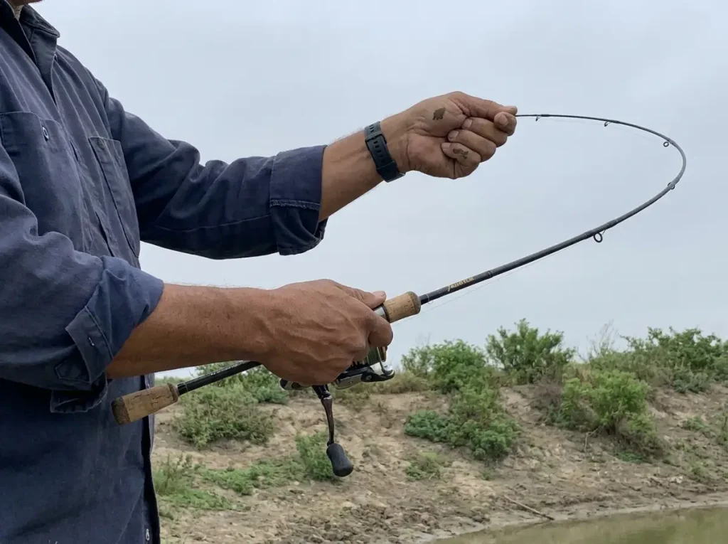 Angler flexing a medium-power spinning rod to check its action, choosing a first fishing rod