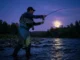 Fishing by the Moon: Solunar Theory & Science Explained Angler fly fishing in a river at night silhouetted against a bright full moon.