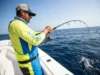 How to Set Fishing Drag: With or Without a Scale Angler fighting a strong fish with a heavily bent rod and tight fishing line, demonstrating proper drag usage.