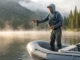Inflatable Fishing Boats Review: Field-Tested Top Picks Angler standing and fly fishing from a stable inflatable skiff on a misty lake at sunrise.