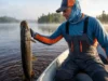 Northern Pike Facts: The Angler’s Tactical Guide An angler holding a large Northern Pike above the water on a foggy lake.