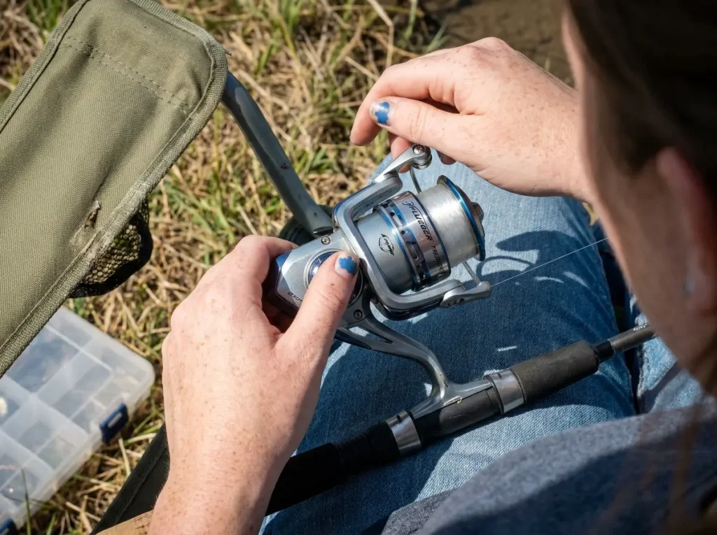 Hands setting the drag on a Pflueger President spinning reel mounted on a beginner rod