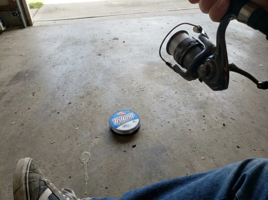 Filler spool lying flat label-up on the floor feeding line onto a spinning reel