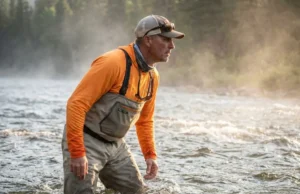 How to Read a River for Fishing: Riffles, Runs & Pools Angler standing in a fast-moving river observing the current flow patterns.