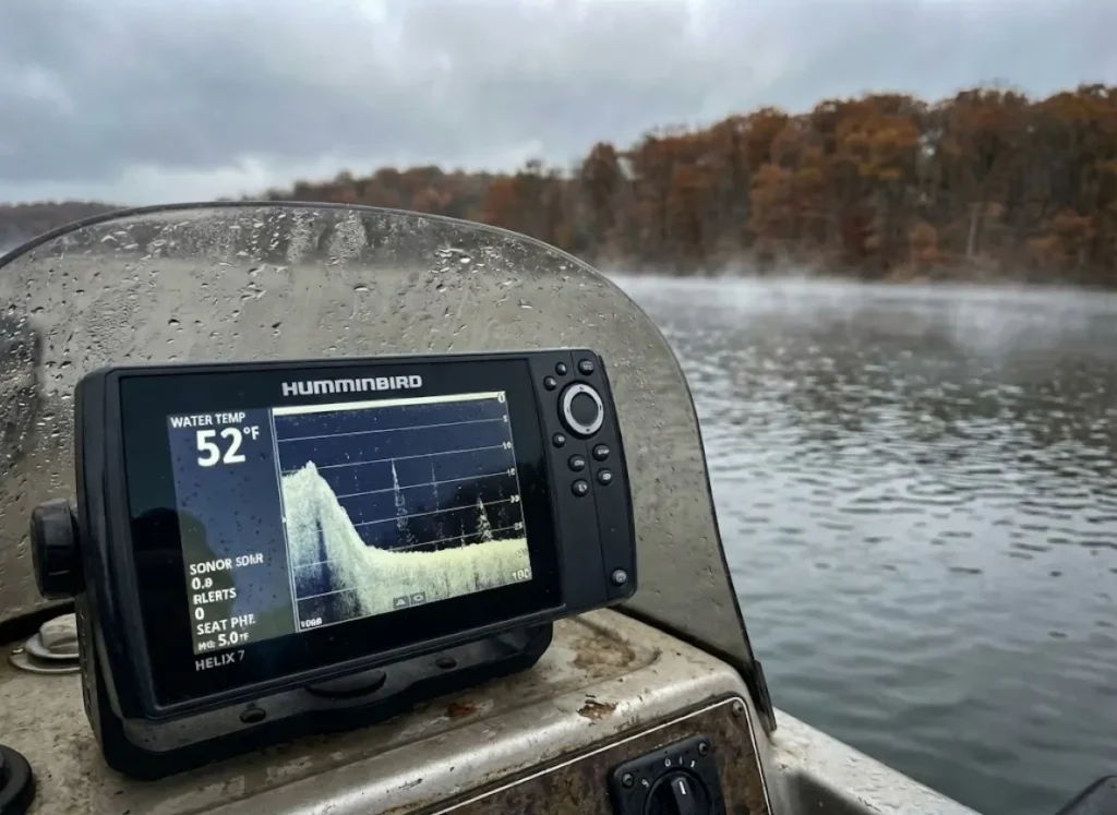 Fish finder screen showing cold water temperature with an autumn lake background.
