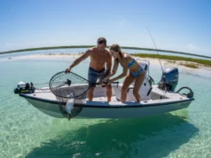 Best Fish-Safe Landing Nets: A Catch & Release Guide A fit couple on a sunny day in a boat, with the man using a rubber landing net to safely bring a fish aboard while the woman watches.