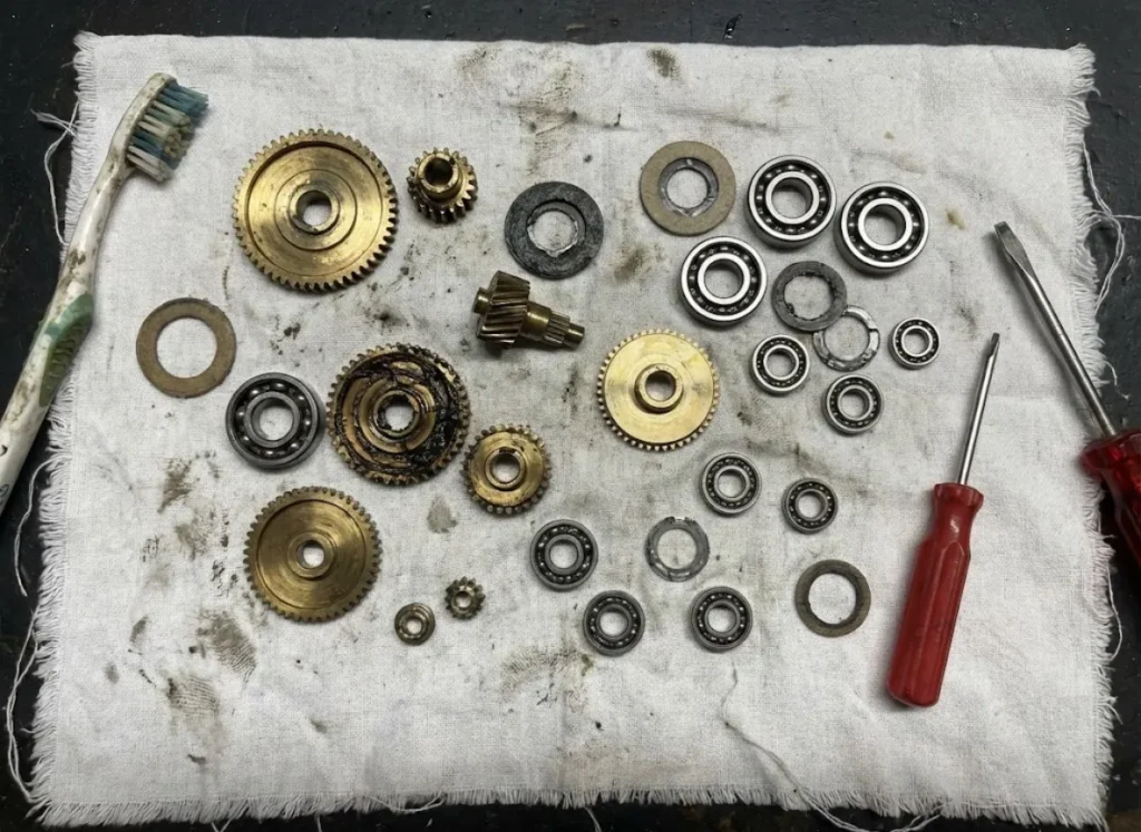 Internal parts of a fishing reel including gears and washers laid out on a shop towel for maintenance.