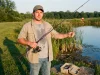 Where Budget Fishing Gear Wins and Where It Fails Angler holding a budget fishing gear combo on a pond bank in late afternoon light