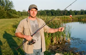 Where Budget Fishing Gear Wins and Where It Fails Angler holding a budget fishing gear combo on a pond bank in late afternoon light