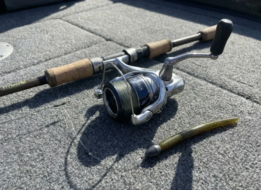 Spinning rod and reel setup for drop shot fishing laying on boat carpet with tungsten weights.