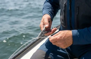 Essential Fishing Tools: Rigging, Handling & Repair Close-up of angler's hands using titanium pliers to rig fishing line on a boat.