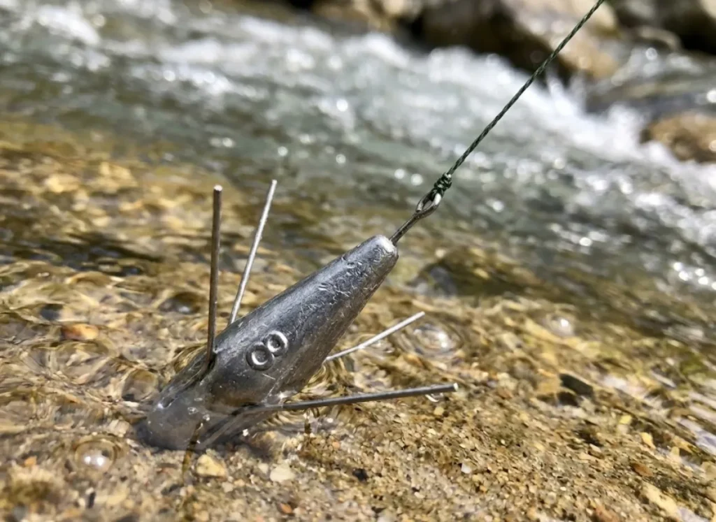 Close-up of a fishing sinker anchored on the river bottom with tight line cutting through the current.