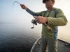 How to Drop Shot: Complete Rigging & Tactical Guide Angler fishing a drop shot rig vertically off the bow of a boat in morning mist.