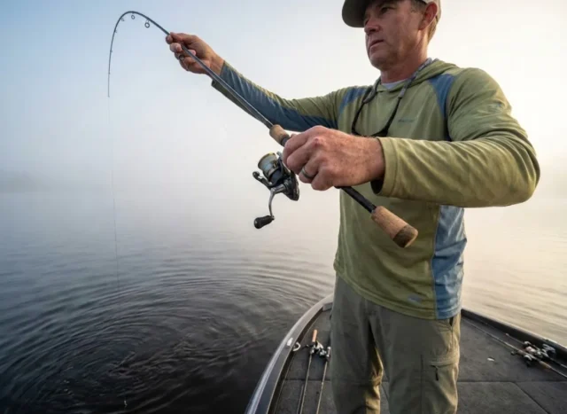 how-to-drop-shot-complete-rigging-tactical-guide Angler fishing a drop shot rig vertically off the bow of a boat in morning mist.