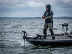 Shallow Water Anchor vs Spot Lock: A Decision Matrix Angler casting from a bass boat in windy conditions, utilizing a trolling motor for position control while shallow water anchors are retracted.