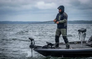 Shallow Water Anchor vs Spot Lock: A Decision Matrix Angler casting from a bass boat in windy conditions, utilizing a trolling motor for position control while shallow water anchors are retracted.