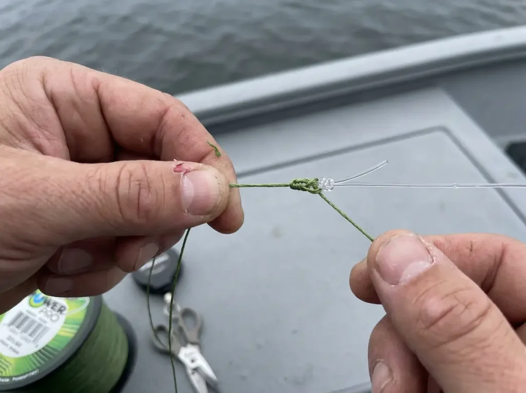 Hands tying a braid-to-fluorocarbon leader knot, the line and leader side of saltwater gear