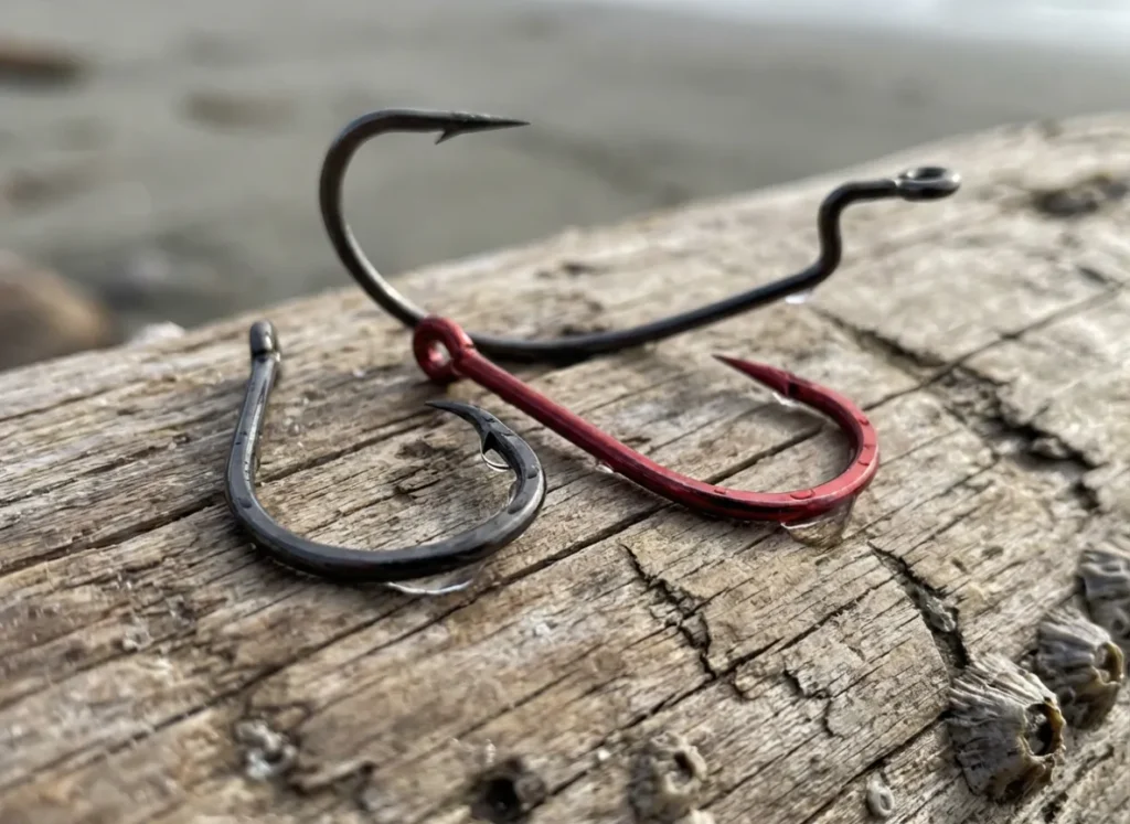 Three different types of fishing hooks arranged on a piece of driftwood.