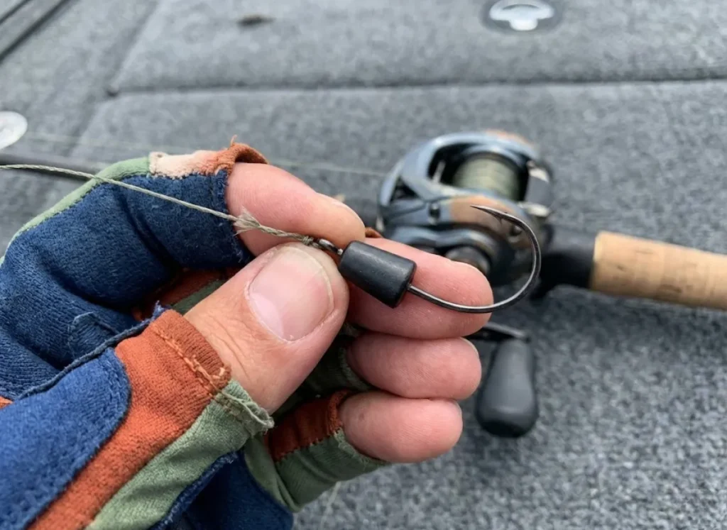 Close-up of a hand holding a fishing line with a heavy tungsten weight pegged to a straight shank hook.