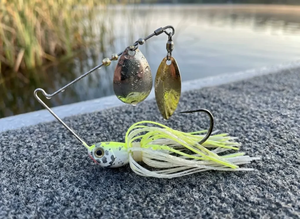 A wet, used white and chartreuse spinnerbait with double willow blades resting on a boat deck.