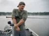 Angler’s Elbow Flaring Up? Check Your Rod Grip First Angler shaking out his casting forearm on a boat deck, rod tucked under his arm on an overcast morning