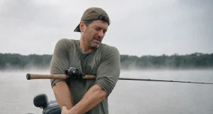 Angler’s Elbow Flaring Up? Check Your Rod Grip First Angler shaking out his casting forearm on a boat deck, rod tucked under his arm on an overcast morning