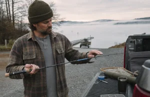 Does Your Fishing Rod Spine Even Matter? Sort Of Angler at a truck tailgate rolling a fishing rod tip to find the blank spine at dawn