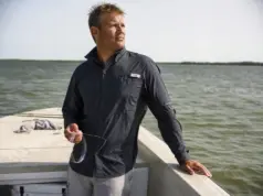 Does UPF Clothing Really Work? The Physics Says Yes Angler in a long sleeve UPF fishing shirt on open water at midmorning, sleeves down against full sun