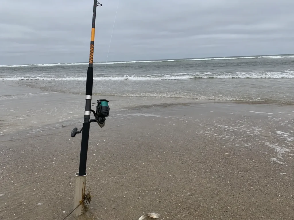 Long surf rod planted in a sand spike on an open beach with the trough behind