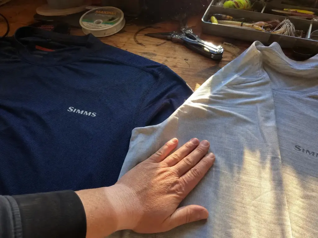 Two UPF fishing shirts laid side by side on a workbench, one tightly woven and one lightweight