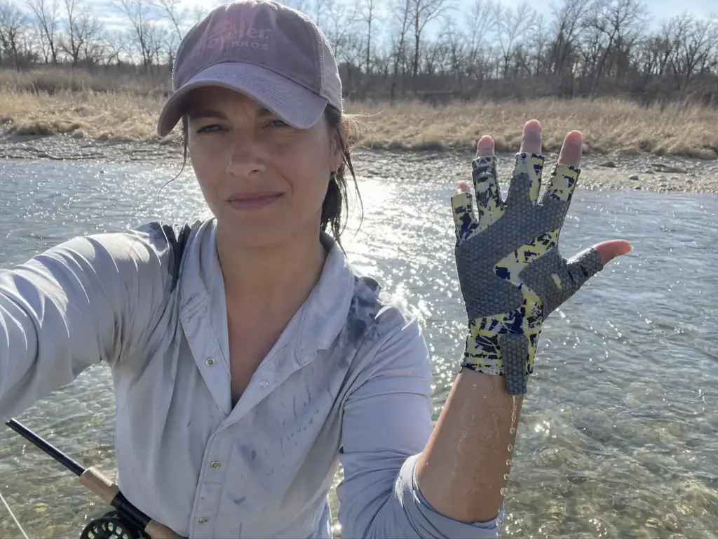 Woman angler holding up a soaked UPF 50 sun glove, showing how wet fabric changes protection